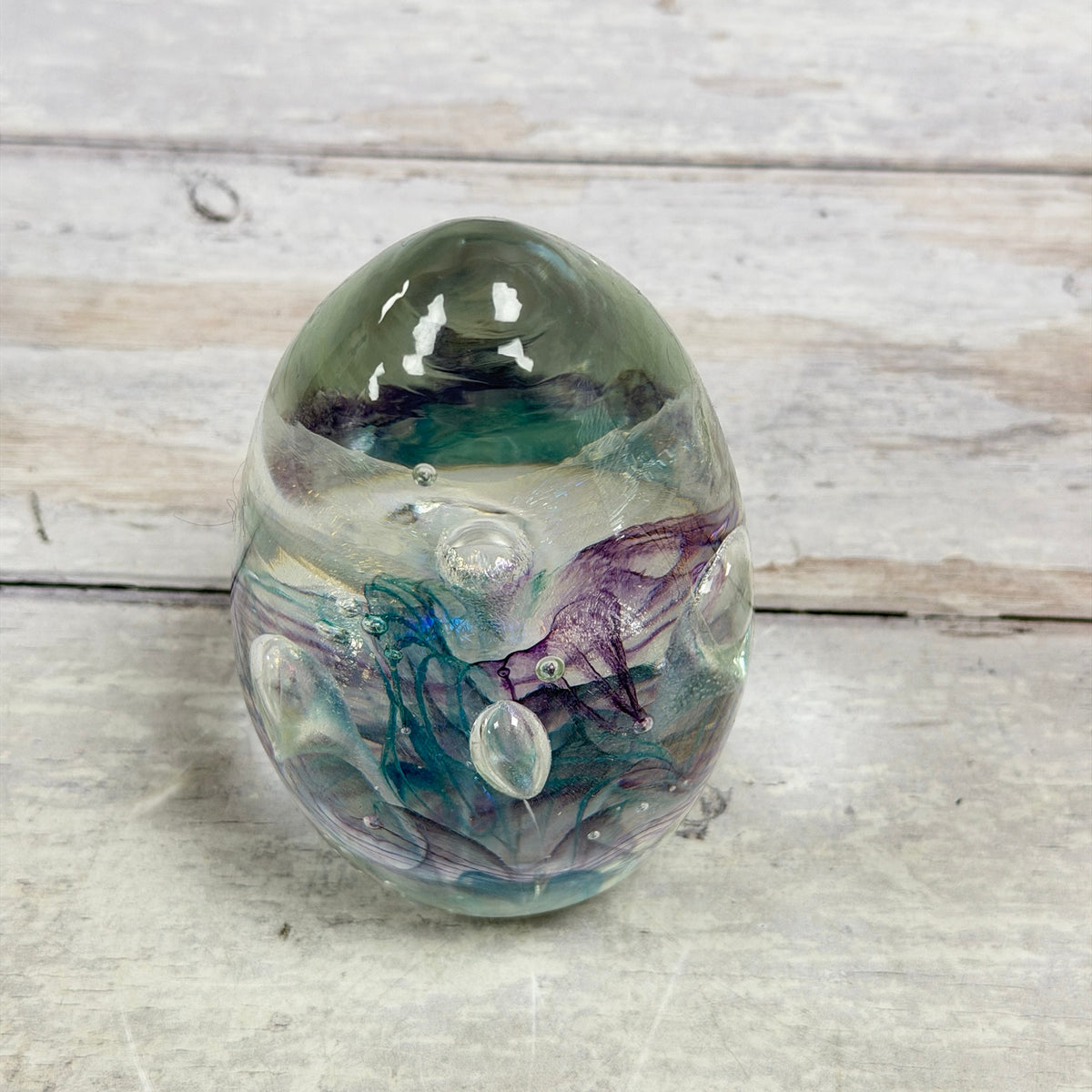 Angled view of signed teal and purple ribbon art glass egg paperweight