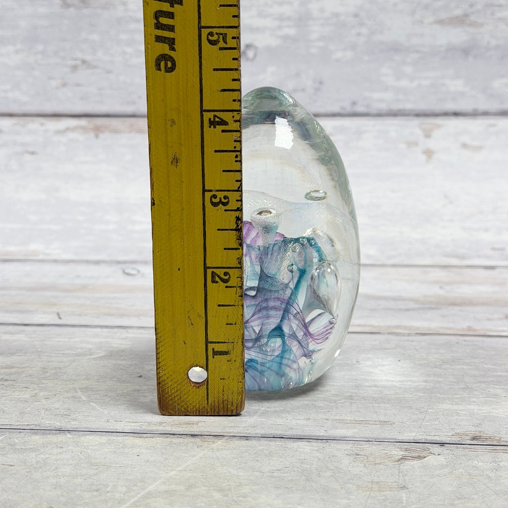 Ribbon and bubble glass egg paperweight beside a ruler showing approximately four and one-quarter inches tall