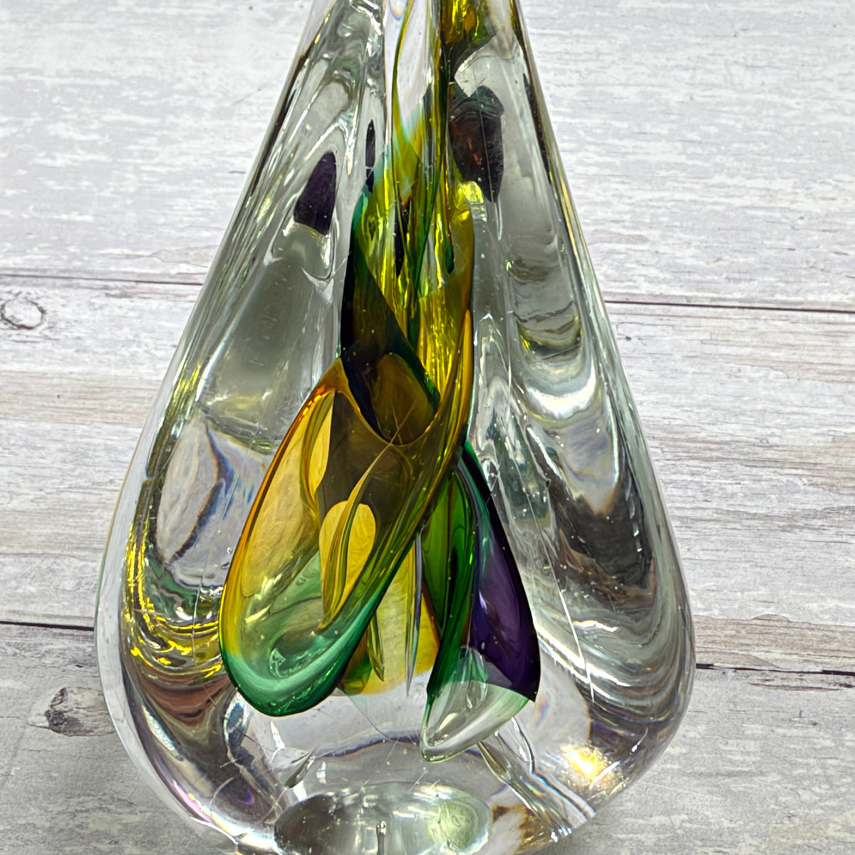 Close-up of internal green, yellow and purple ribbons in clear teardrop crystal paperweight