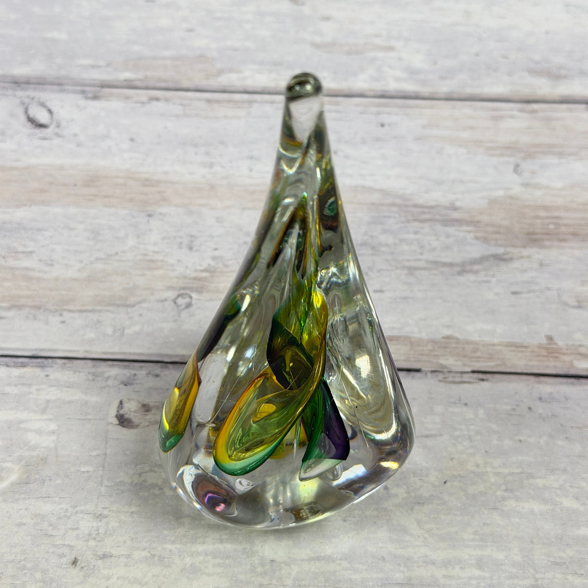 Reverse view of multicolor teardrop glass paperweight showing curved green and yellow ribbons