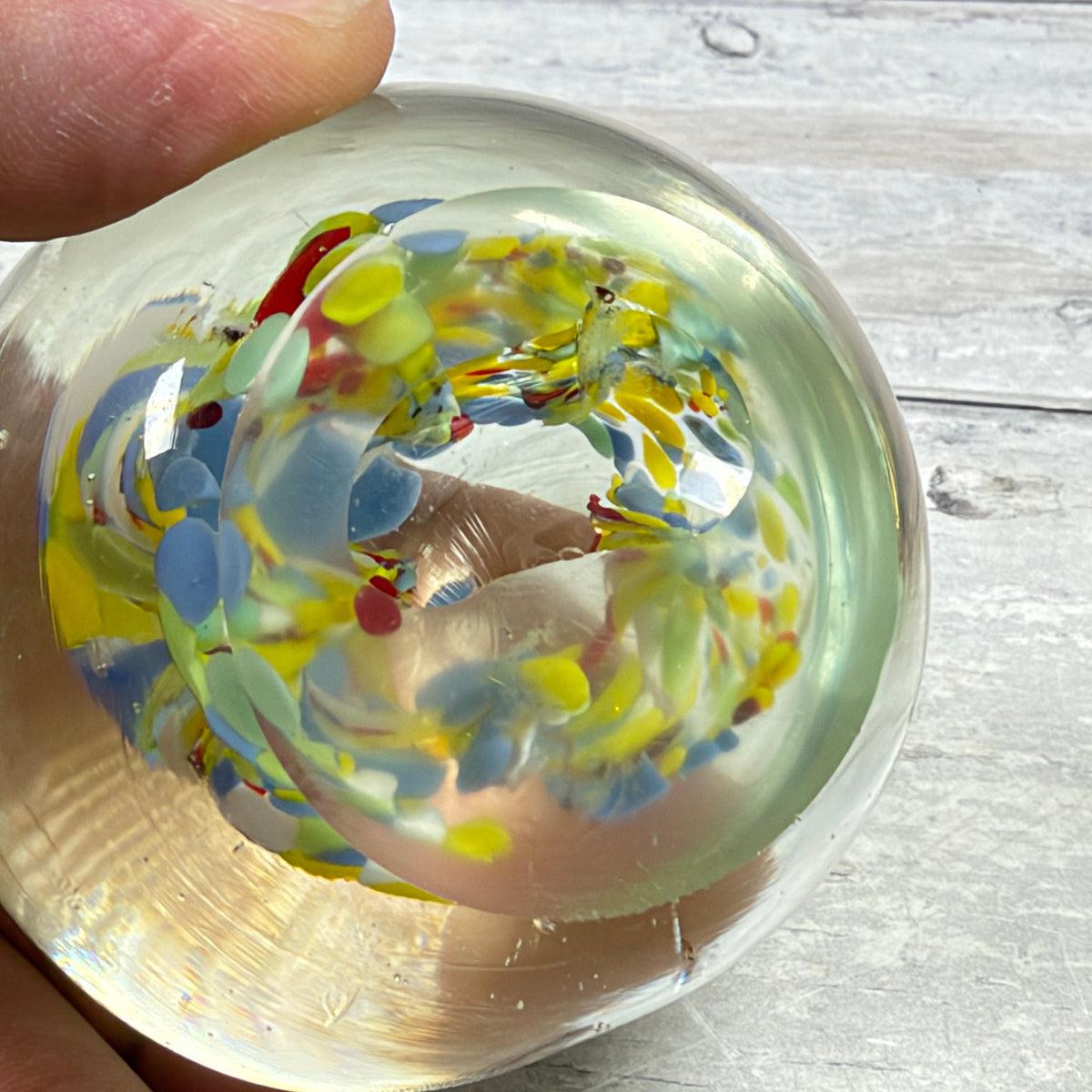 Underside of unsigned confetti glass paperweight showing flat base, fine scratches and small edge marks