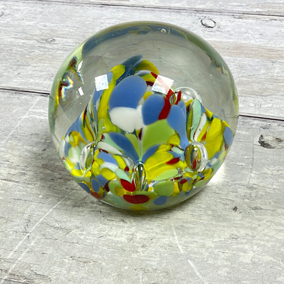 Reverse view of multicolor confetti art glass paperweight showing petal-like shapes and suspended air bubbles