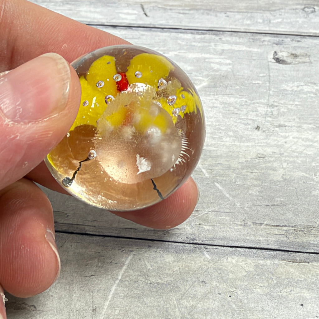 Underside of unsigned butterfly glass paperweight showing ground base, surface wear and a small white residue patch