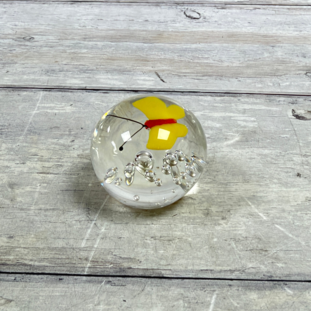 Mini clear glass paperweight with a yellow butterfly, red body, black antennae and controlled bubbles