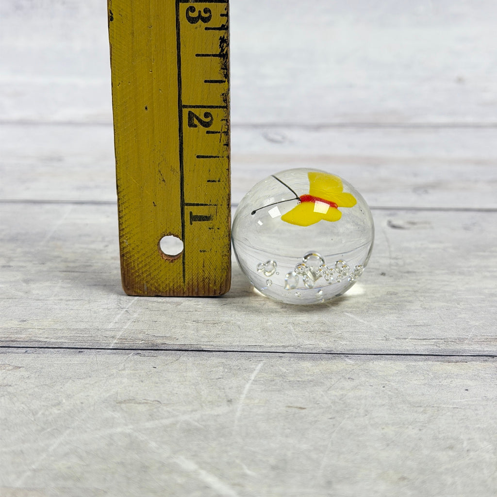 Small yellow butterfly glass paperweight beside a ruler, approximately one and a half inches tall