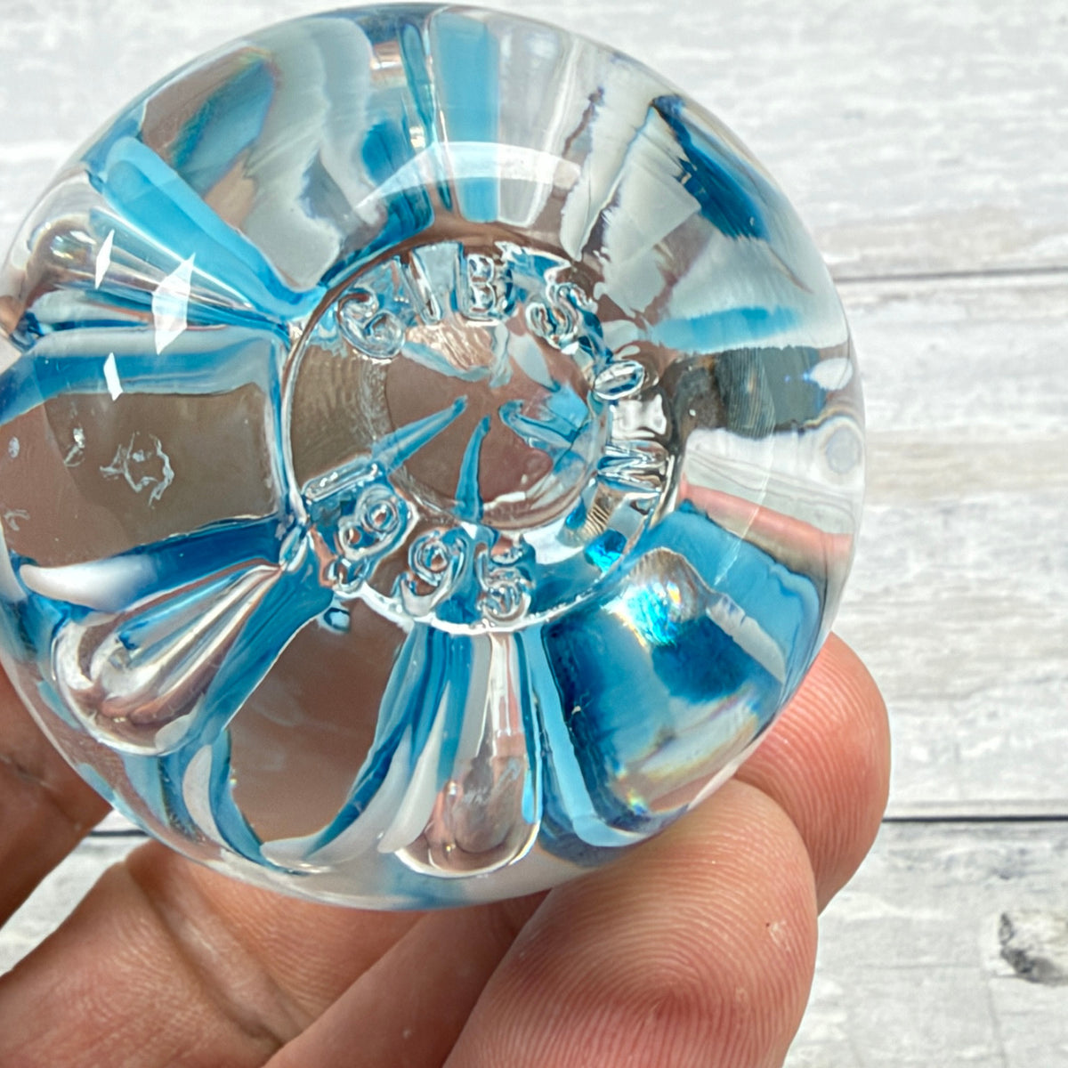 Underside of glass paperweight showing the molded GIBSON 1995 maker and date mark with light base wear