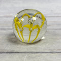 Clear glass paperweight with bright yellow ribbon loops and controlled bubbles