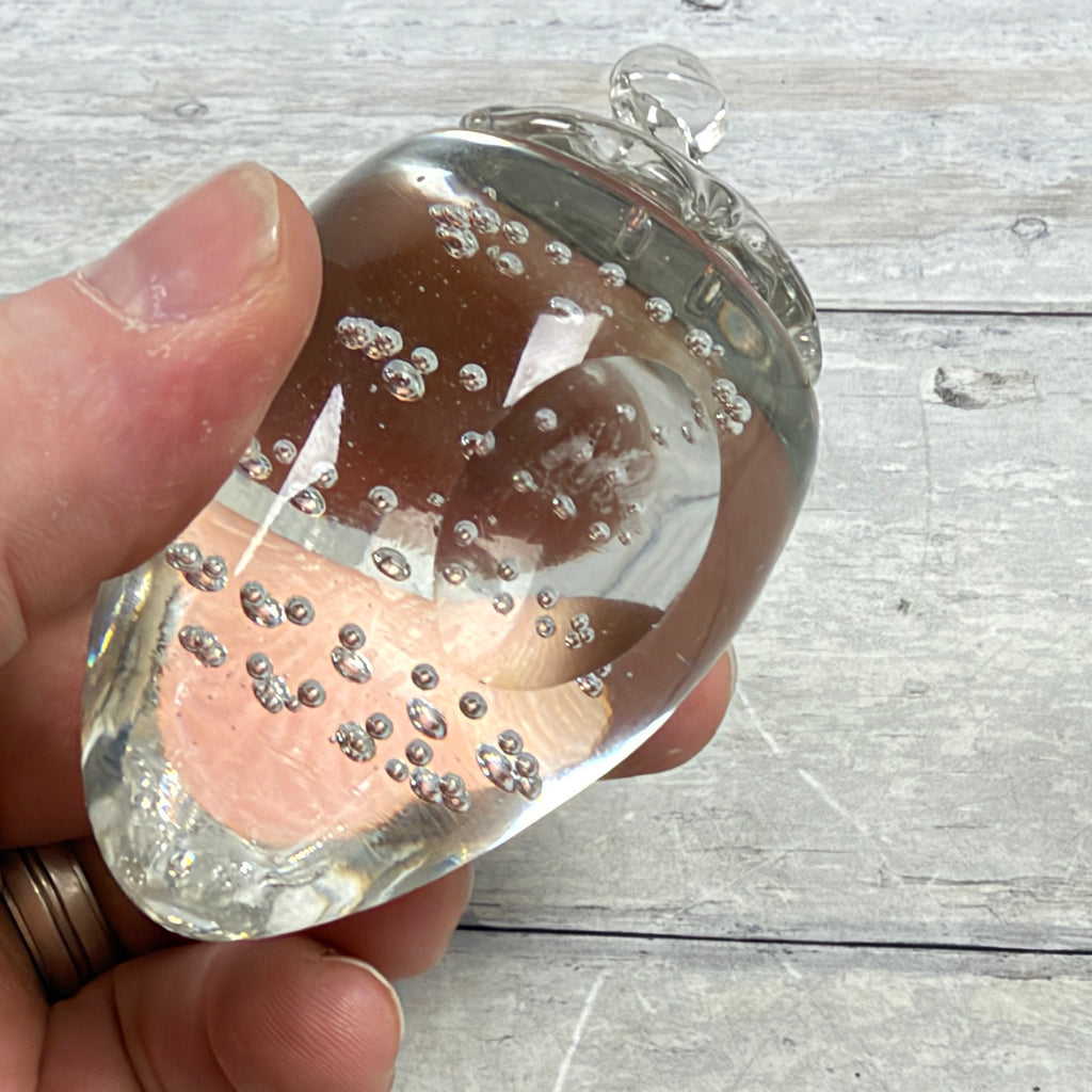 Clear strawberry-shaped glass paperweight with controlled bubbles, underside detail