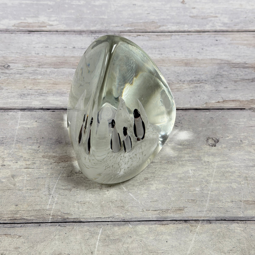 Angled view of four penguins encased in clear art glass with white iceberg decoration