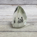 Clear teardrop glass paperweight with four black-and-white penguins in a snowy white scene