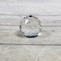 Clear faceted glass paperweight with triangular facets and blue-purple reflections