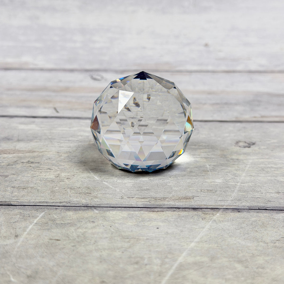Clear faceted glass paperweight with triangular facets and blue-purple reflections