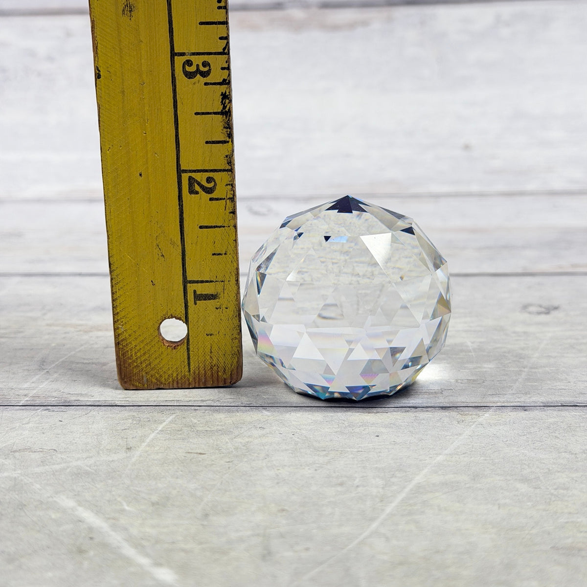 Clear faceted glass paperweight beside a ruler showing approximately one and three-quarter inches tall