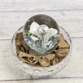 White trumpet-flower glass paperweight with blue and green frit, elevated front view; display bowl not included