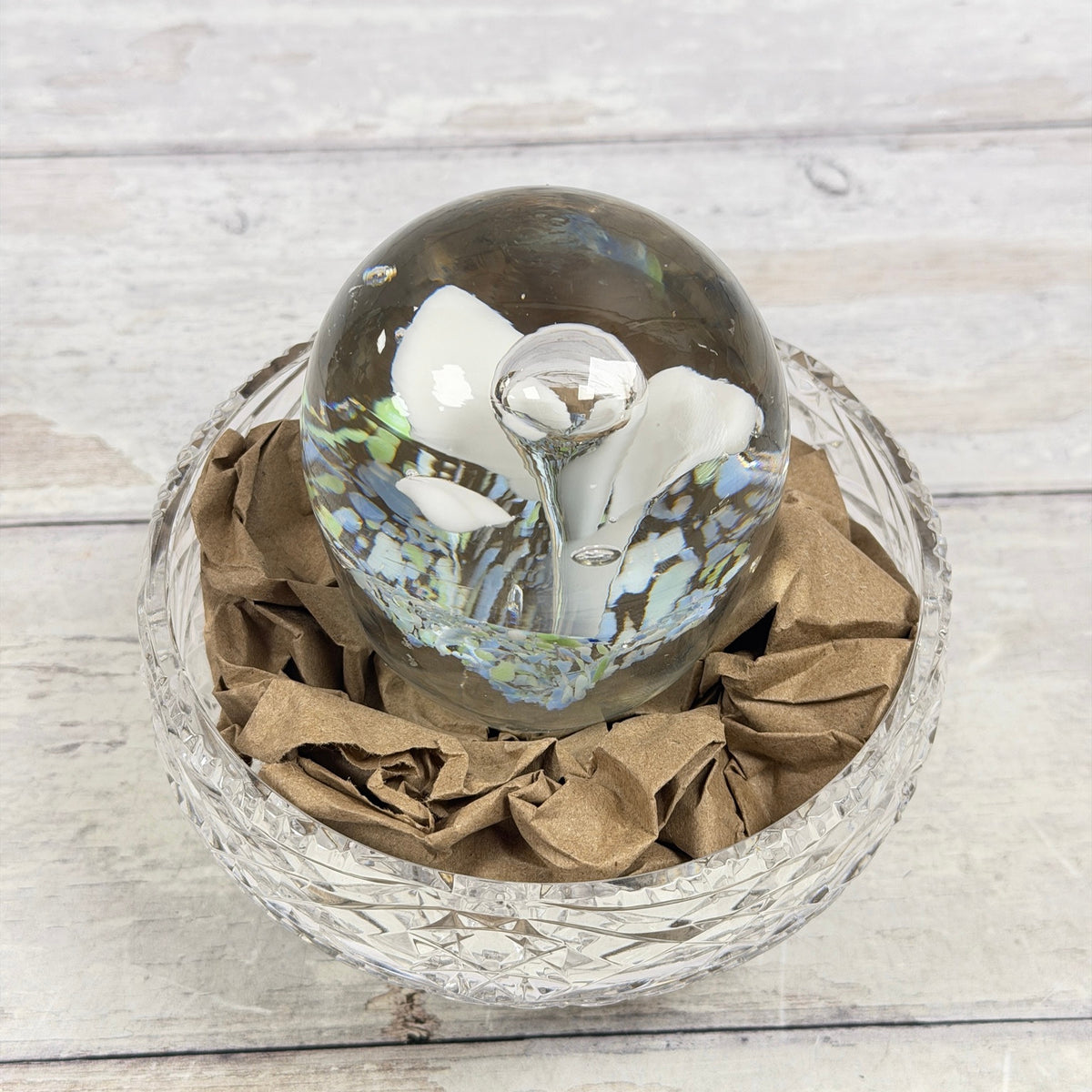 White trumpet-flower glass paperweight with blue and green frit, elevated front view; display bowl not included